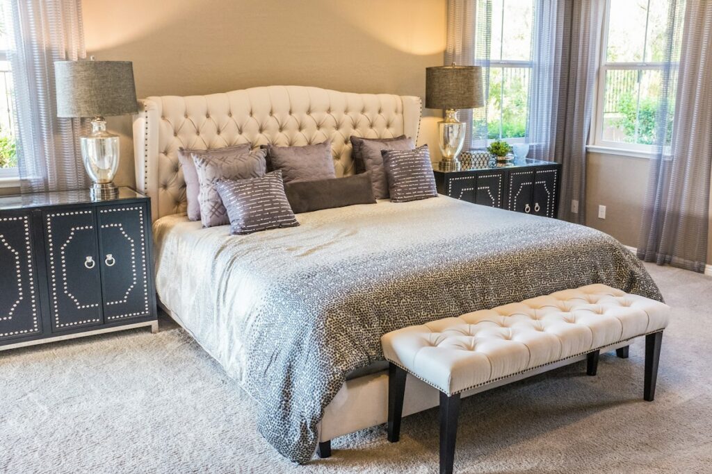 Clean bedroom with crisp linen bedding, wooden side table, and soft bedside light