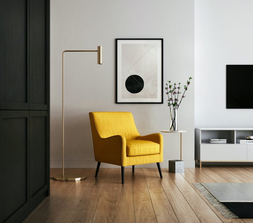 Warm reading nook with soft upholstered chair, floor lamp, and stacked books