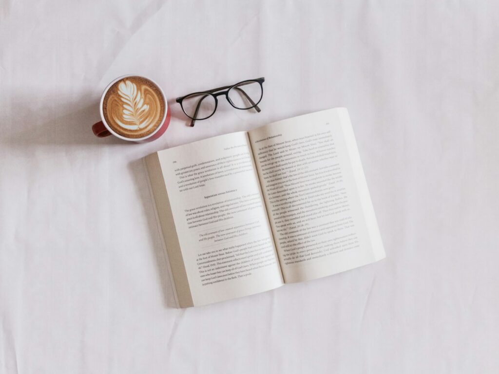 Minimalist digital e-reader resting on linen bed sheets beside a book